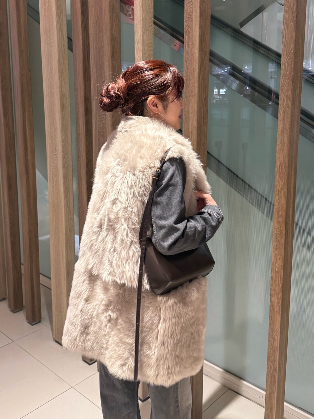 グレー系のデニムジャケット、グレー系のデニムパンツ、ベージュ系のベストを着用したレディースの冬コーディネートの4枚目の写真