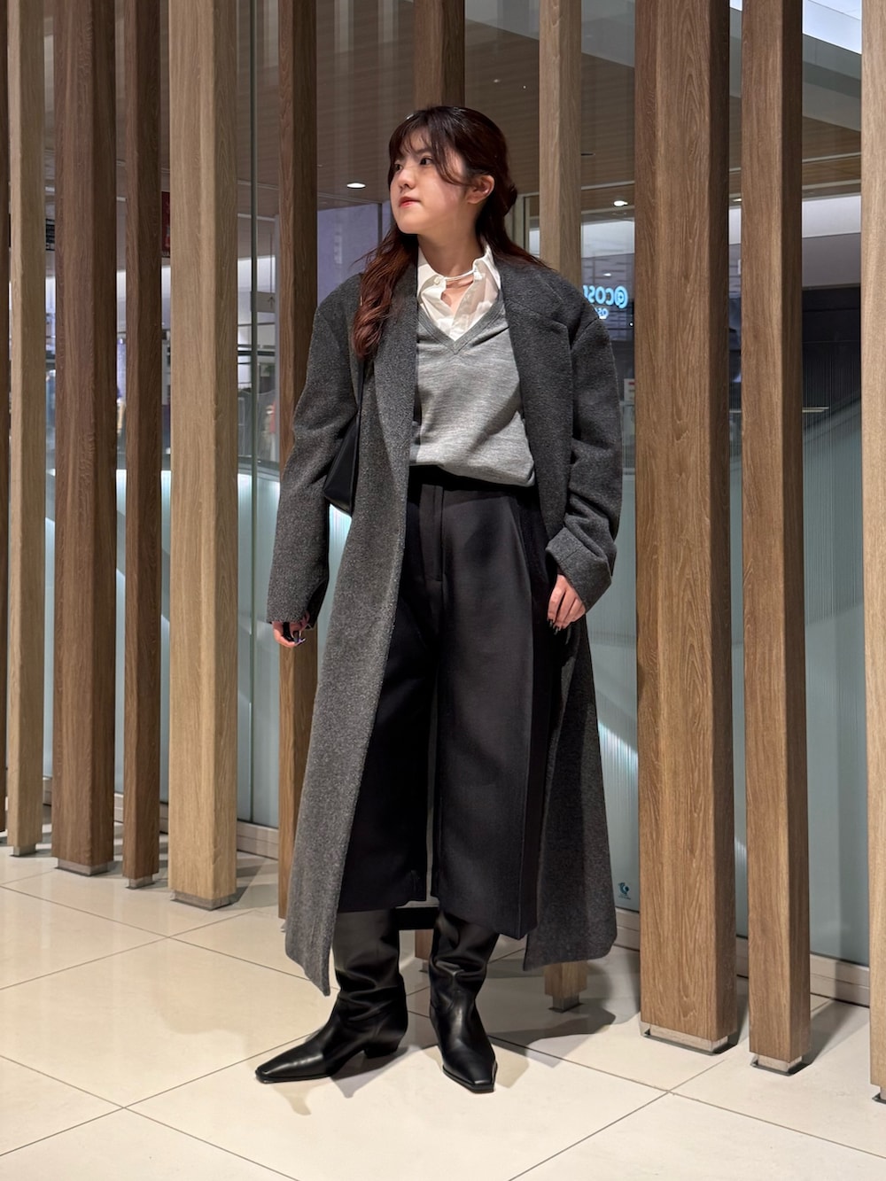 グレー系のニット/セーター、グレー系のチェスターコート、ブラック系のその他パンツを着用したレディースの冬コーディネートの3枚目の写真