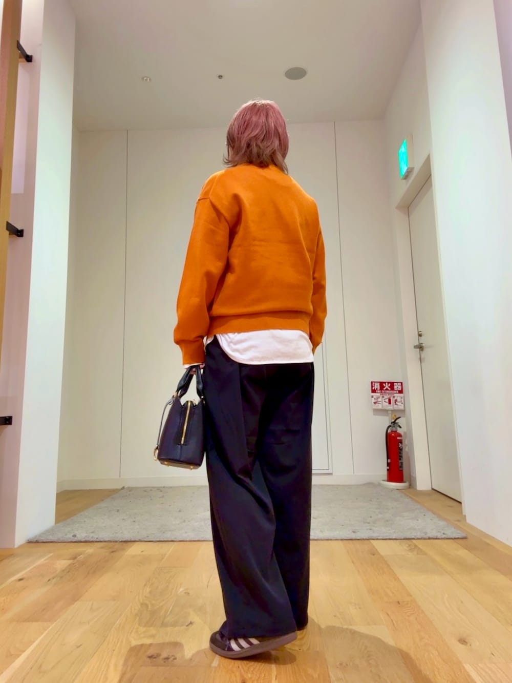 ブラック系のハンドバッグ、ホワイト系のTシャツ/カットソー、ベージュ系のステンカラーコートを着用したレディースの秋コーディネートの5枚目の写真