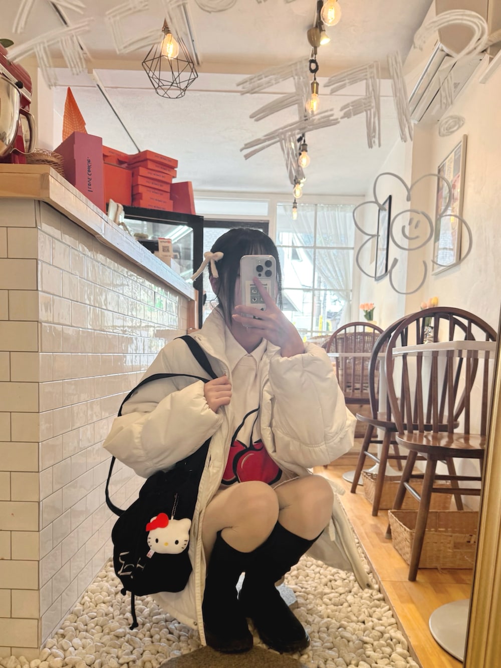 ブラック系のブーツ、ホワイト系のその他アウター、ホワイト系のスカートを着用したレディースの冬コーディネートの2枚目の写真