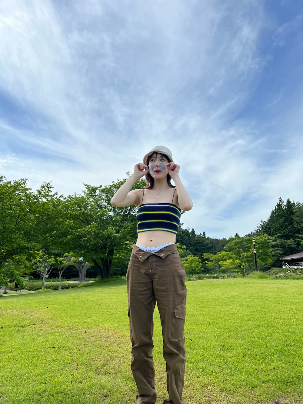 ブルー系のキャミソール、ブラウン系のカーゴパンツ、ホワイト系のハットを着用したレディースの夏コーディネートの2枚目の写真