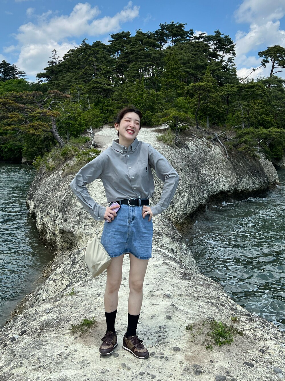 グレー系のシャツ/ブラウス、ブルー系のデニムスカート、ブラウン系のスニーカーを着用したレディースの夏コーディネートの2枚目の写真