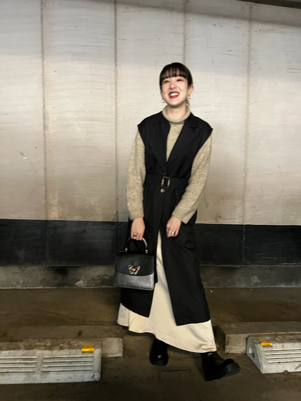 ブラック系のハンドバッグ、ブラック系のトレンチコート、ホワイト系のスカートを着用したレディースの春コーディネートの2枚目の写真