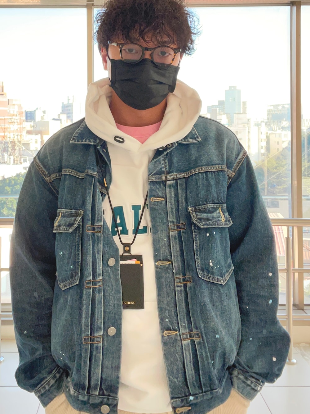 ブルー系のデニムジャケット、ホワイト系のパーカー、ホワイト系のスニーカーを着用したメンズの秋コーディネートの2枚目の写真