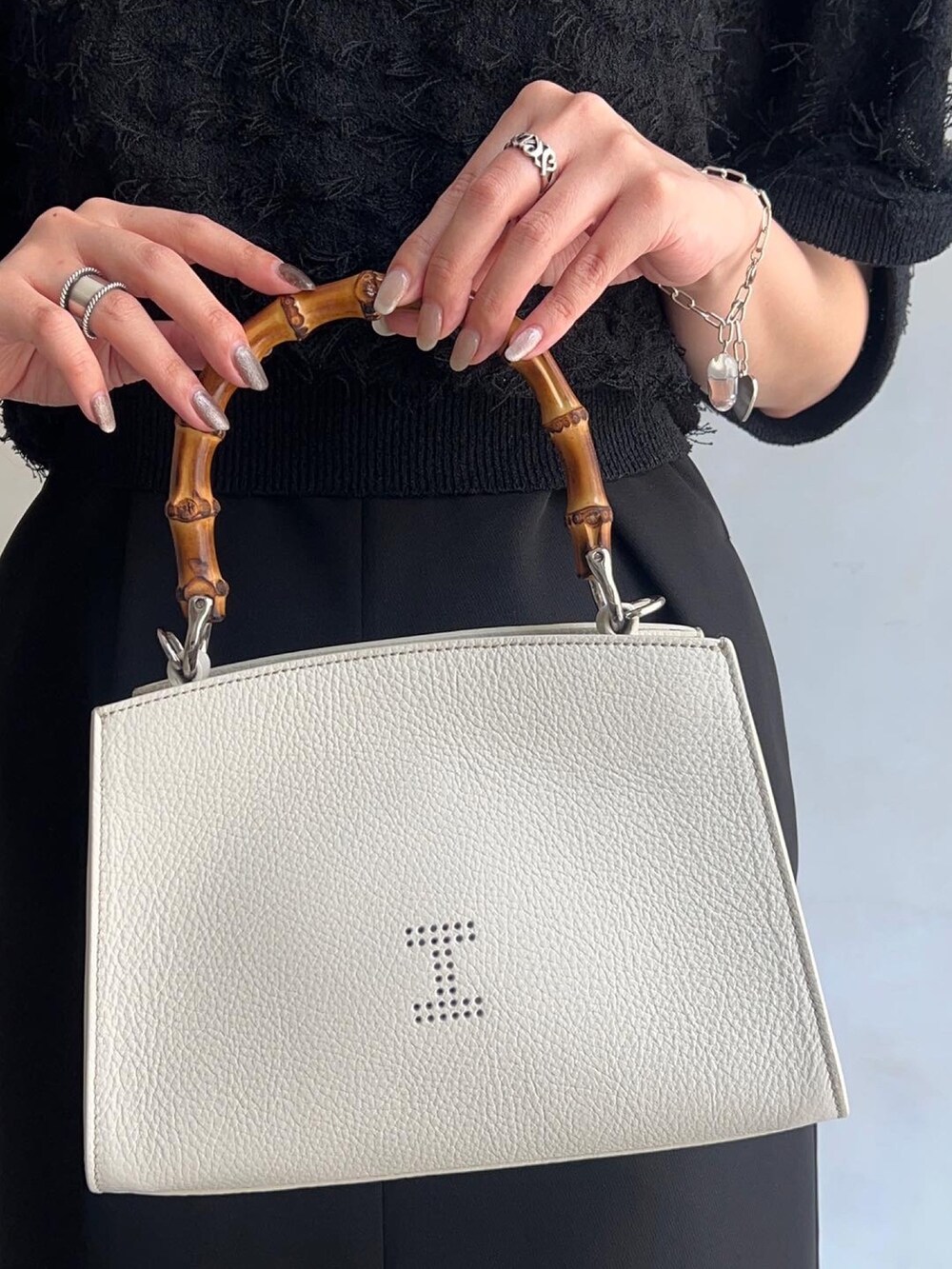 ホワイト系のトートバッグ、ブラック系のワンピース、ブラック系のニット/セーターを着用したレディースの春コーディネートの3枚目の写真