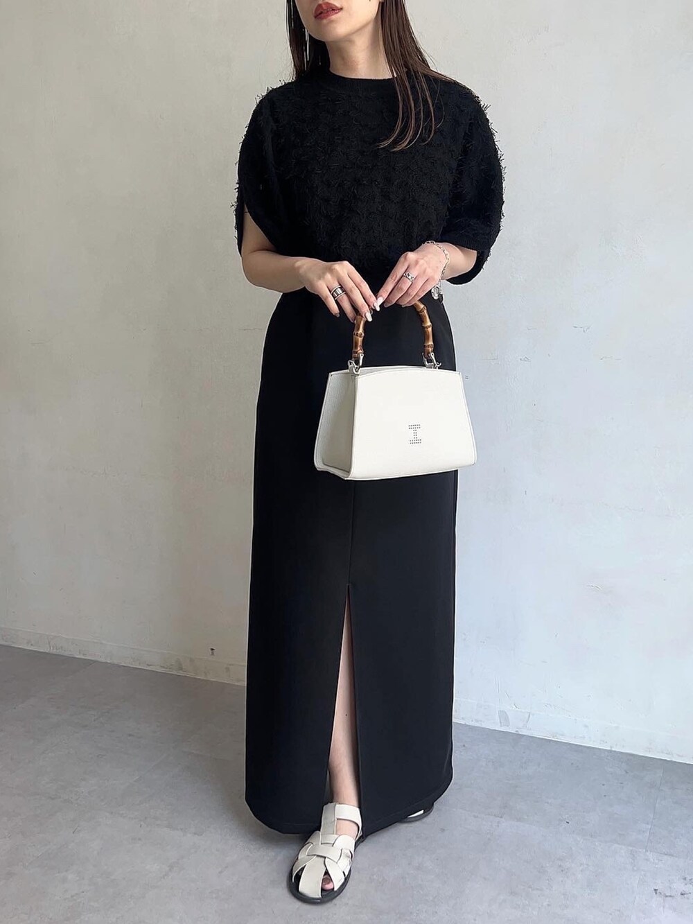 ホワイト系のトートバッグ、ブラック系のワンピース、ブラック系のニット/セーターを着用したレディースの春コーディネートの2枚目の写真