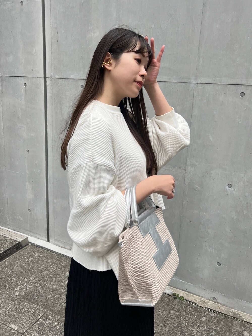 シルバー系のトートバッグ、ホワイト系のTシャツ/カットソー、ブラック系のスカートを着用したレディースの春コーディネートの2枚目の写真