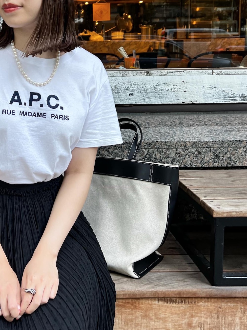 ブラック系のトートバッグ、ブラック系のスカート、ホワイト系のサンダルを着用したレディースの夏コーディネートの2枚目の写真