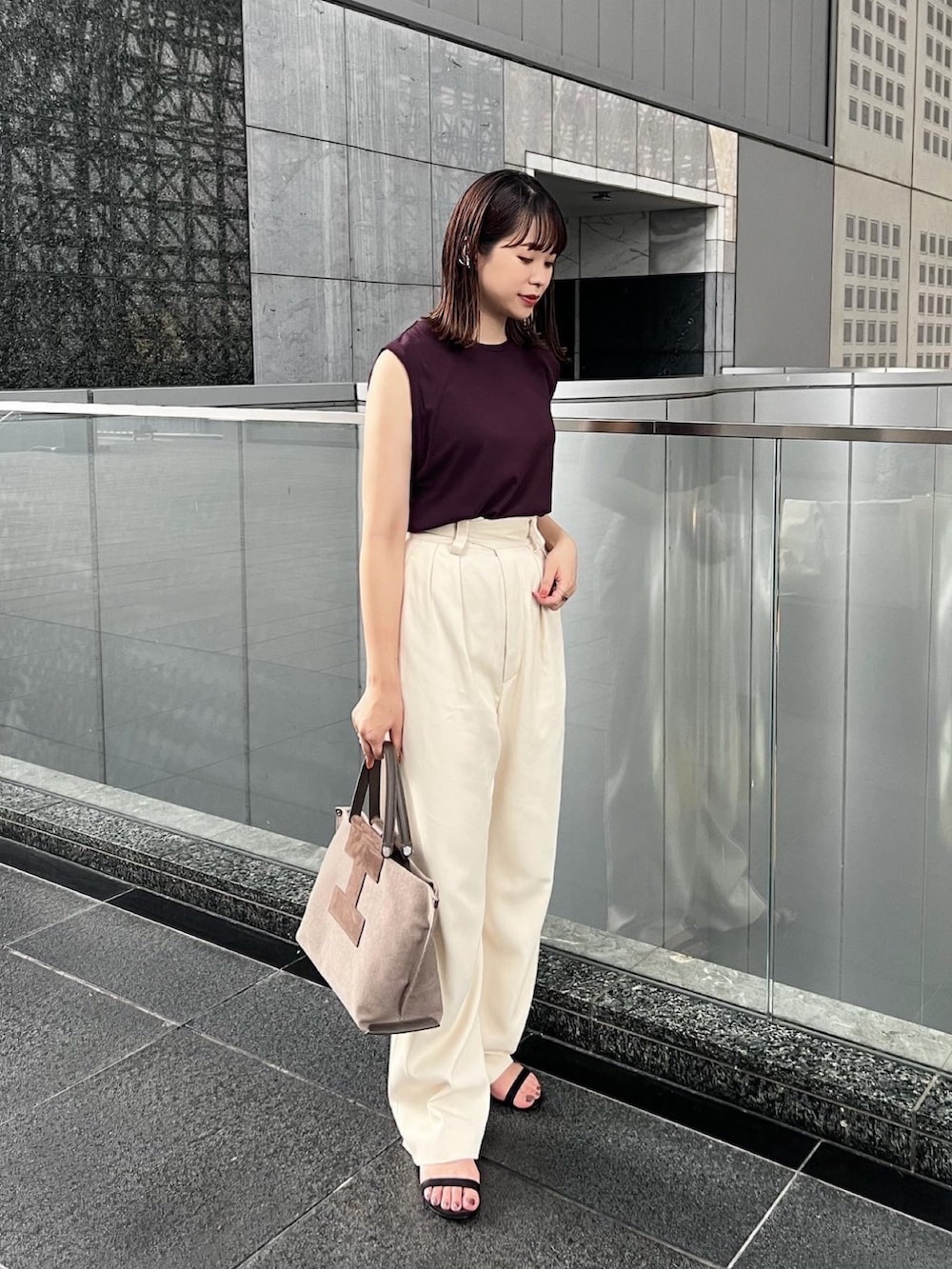 ブラウン系のトートバッグ、ホワイト系のその他パンツ、ブラック系のサンダルを着用したレディースの夏コーディネートの2枚目の写真