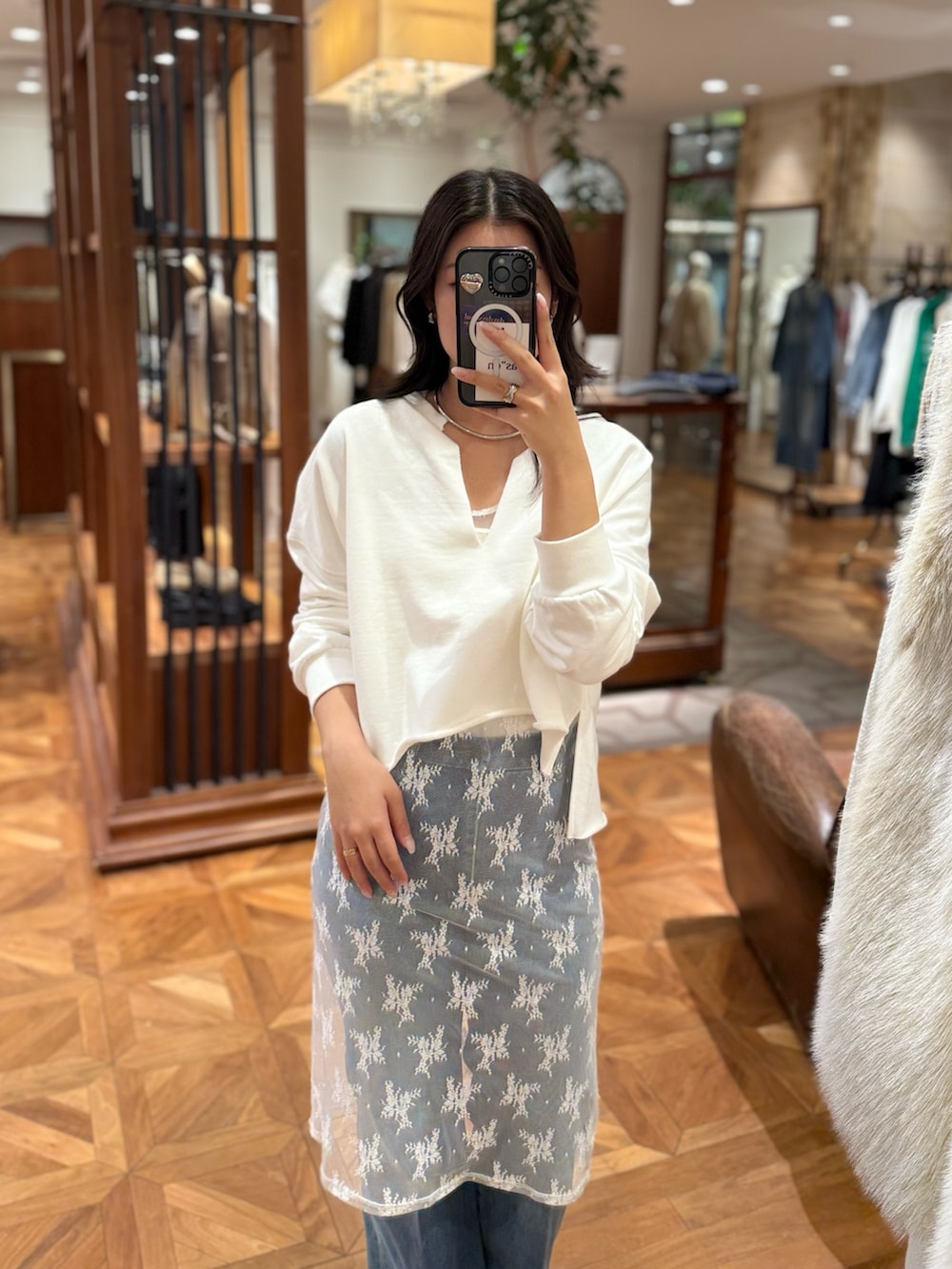 ホワイト系のチュニック、ホワイト系のスウェット、ブルー系のデニムパンツを着用したレディースの冬コーディネートの2枚目の写真