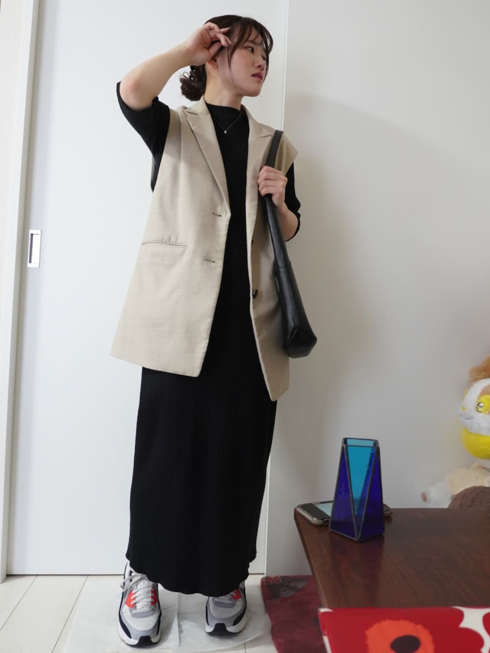 ベージュ系のベスト、ブラック系のワンピース、その他のスニーカーを着用したレディースの春コーディネートの2枚目の写真