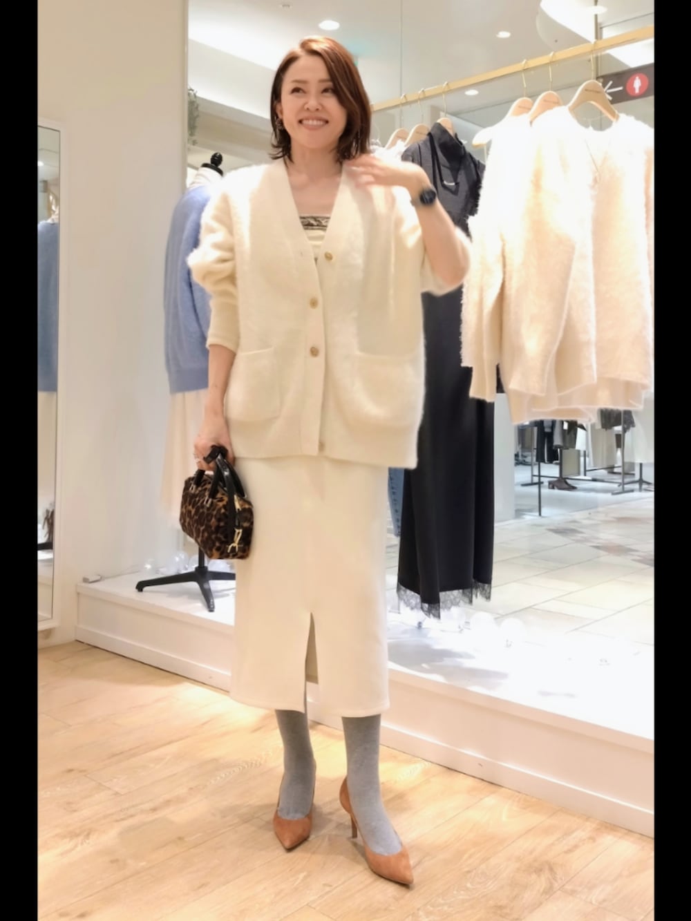 ホワイト系のカーディガン/ボレロ、ホワイト系のスカート、ブラウン系のバッグを着用したレディースの冬コーディネートの6枚目の写真