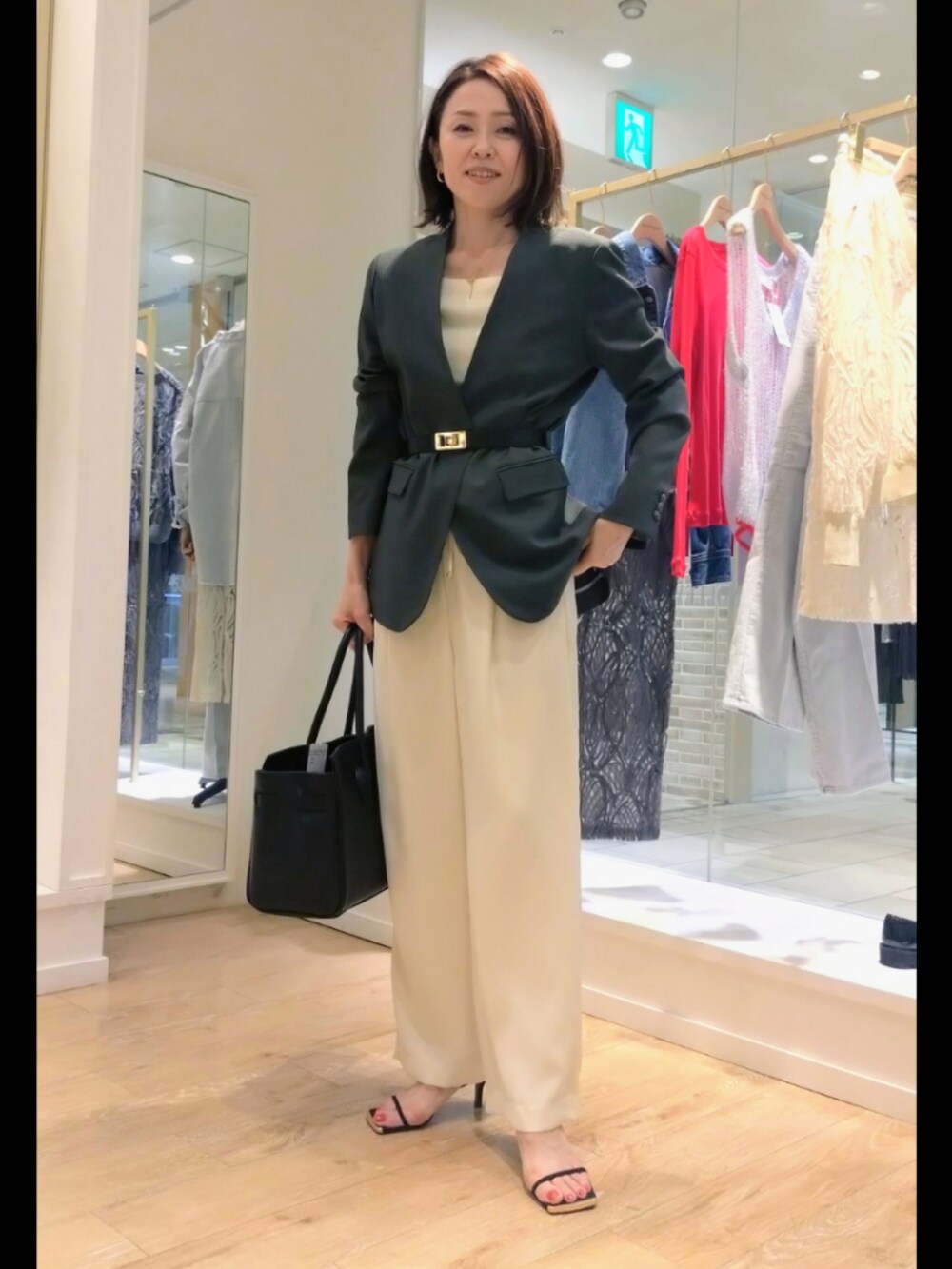 グレー系のノーカラージャケット、ホワイト系のニット/セーター、ブラック系のトートバッグを着用したレディースの秋コーディネートの2枚目の写真