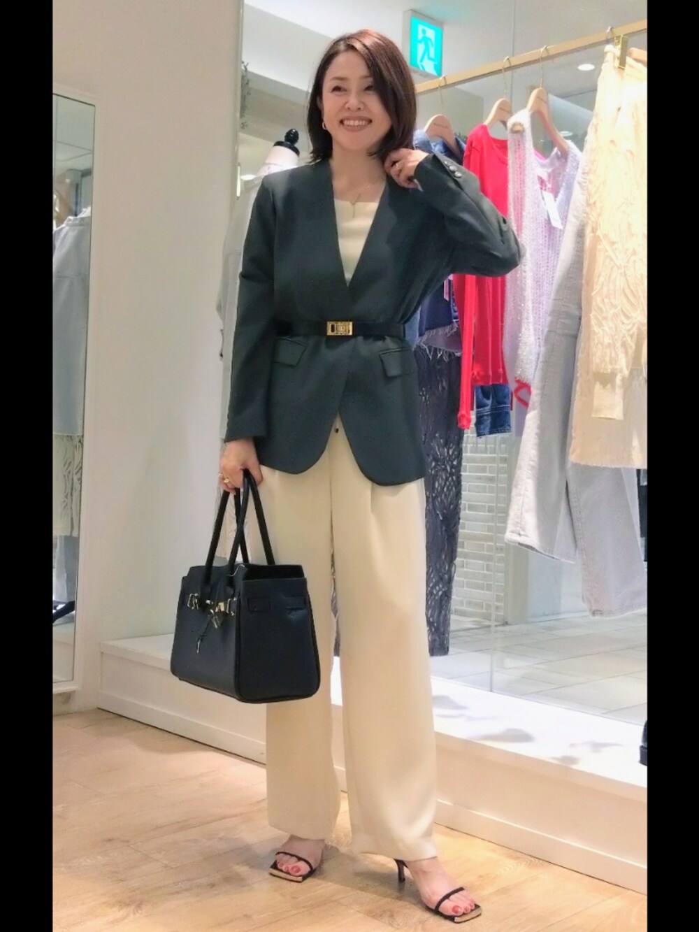 グレー系のノーカラージャケット、ホワイト系のニット/セーター、ブラック系のトートバッグを着用したレディースの秋コーディネートの3枚目の写真