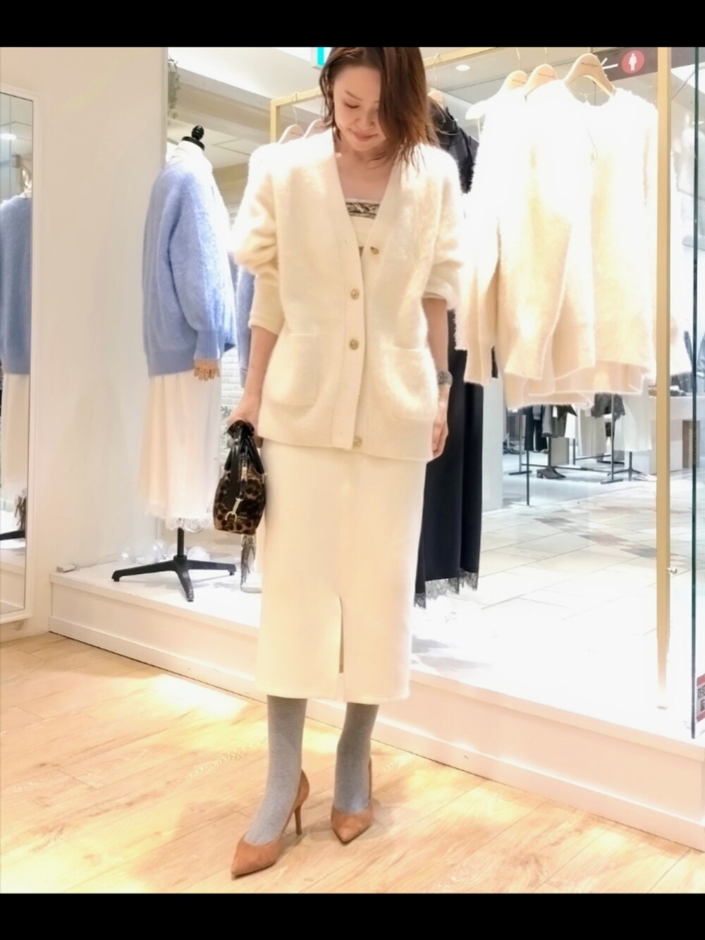 ホワイト系のカーディガン/ボレロ、ホワイト系のスカート、ブラウン系のバッグを着用したレディースの冬コーディネートの2枚目の写真