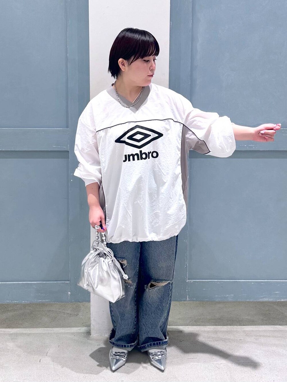 シルバー系のパンプス、シルバー系のショルダーバッグ、ブルー系のデニムパンツを着用したレディースの秋コーディネートの5枚目の写真