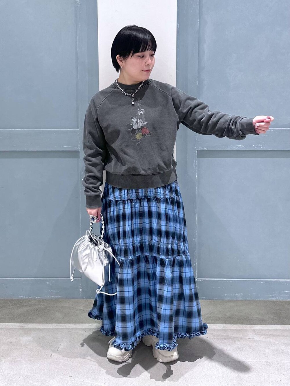 ブルー系のスカート、シルバー系のショルダーバッグ、ホワイト系のスニーカーを着用したレディースの夏コーディネートの5枚目の写真