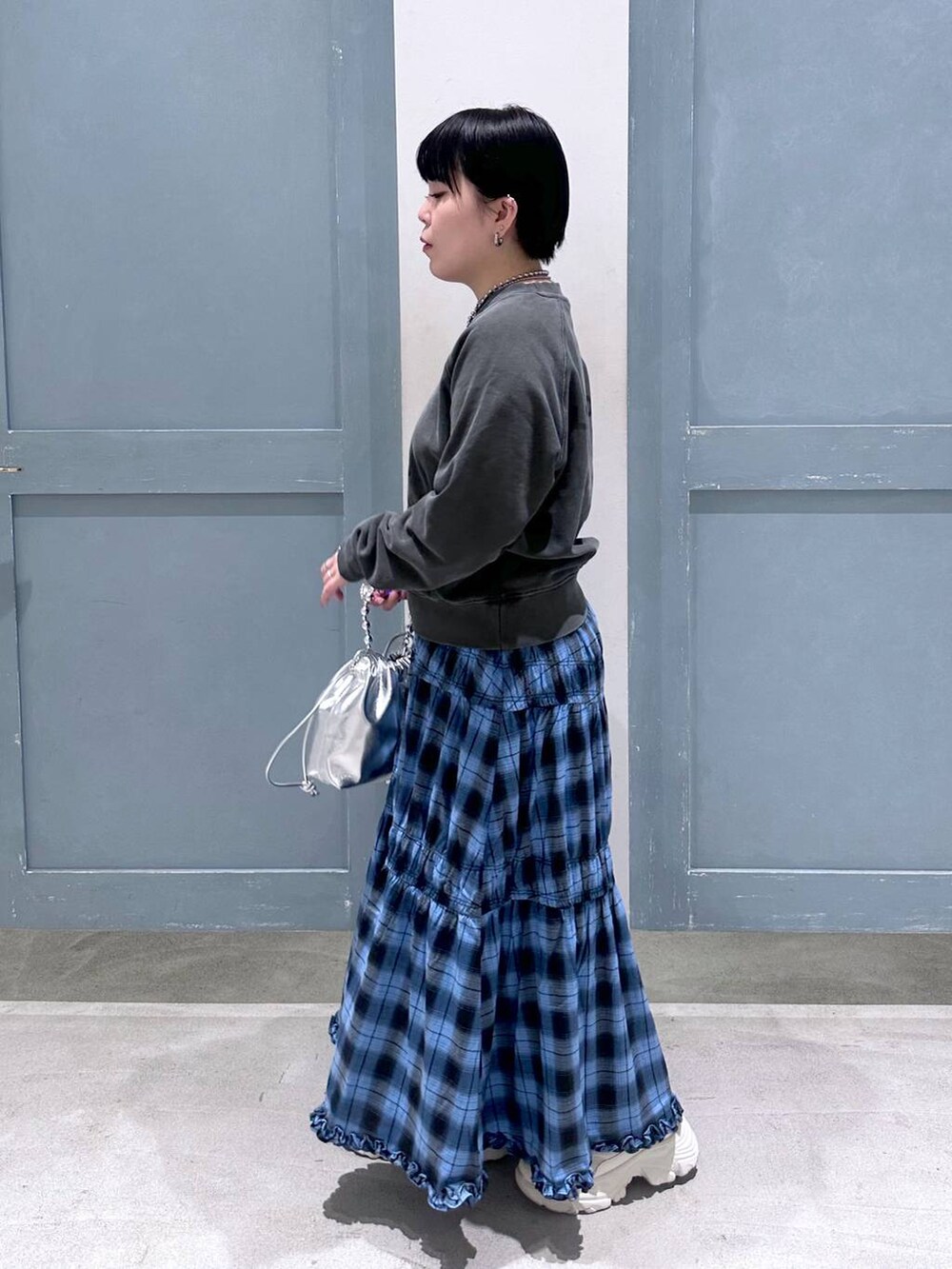 ブルー系のスカート、シルバー系のショルダーバッグ、ホワイト系のスニーカーを着用したレディースの夏コーディネートの3枚目の写真