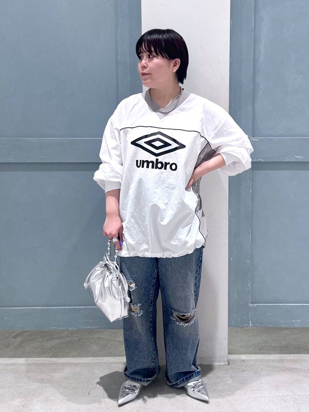 シルバー系のパンプス、シルバー系のショルダーバッグ、ブルー系のデニムパンツを着用したレディースの秋コーディネートの2枚目の写真