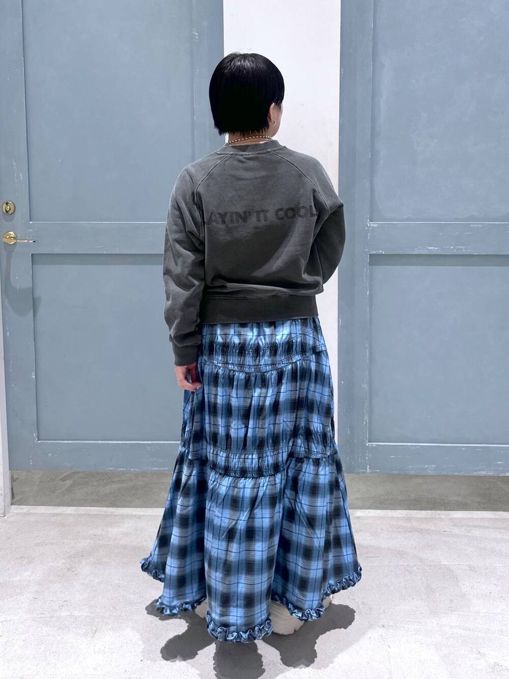 ブルー系のスカート、シルバー系のショルダーバッグ、ホワイト系のスニーカーを着用したレディースの夏コーディネートの4枚目の写真