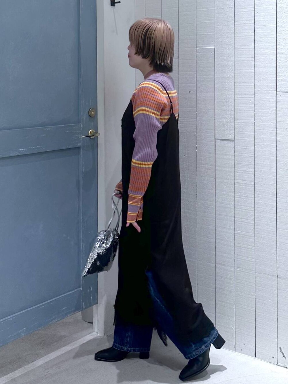 ブルー系のデニムパンツ、ブラック系のパンプス、シルバー系のハンドバッグを着用したレディースの秋コーディネートの4枚目の写真