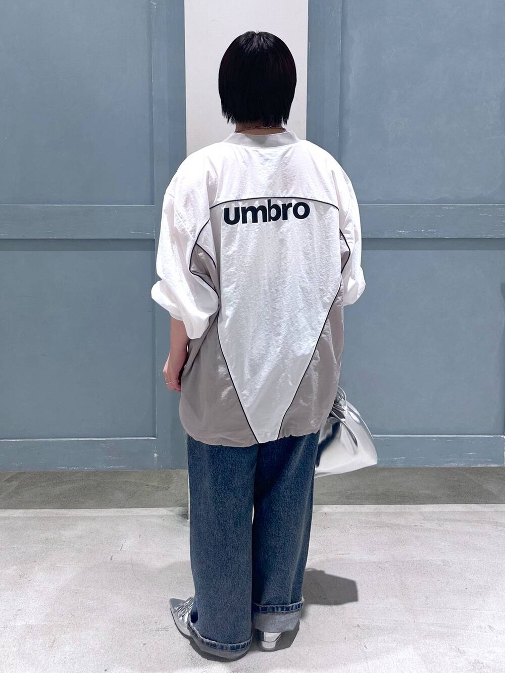 シルバー系のパンプス、シルバー系のショルダーバッグ、ブルー系のデニムパンツを着用したレディースの秋コーディネートの4枚目の写真