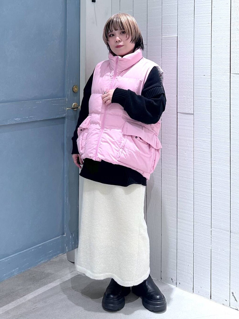 ピンク系のダウンベスト、ブラック系のTシャツ/カットソー、ホワイト系のスカートを着用したレディースの秋コーディネートの4枚目の写真