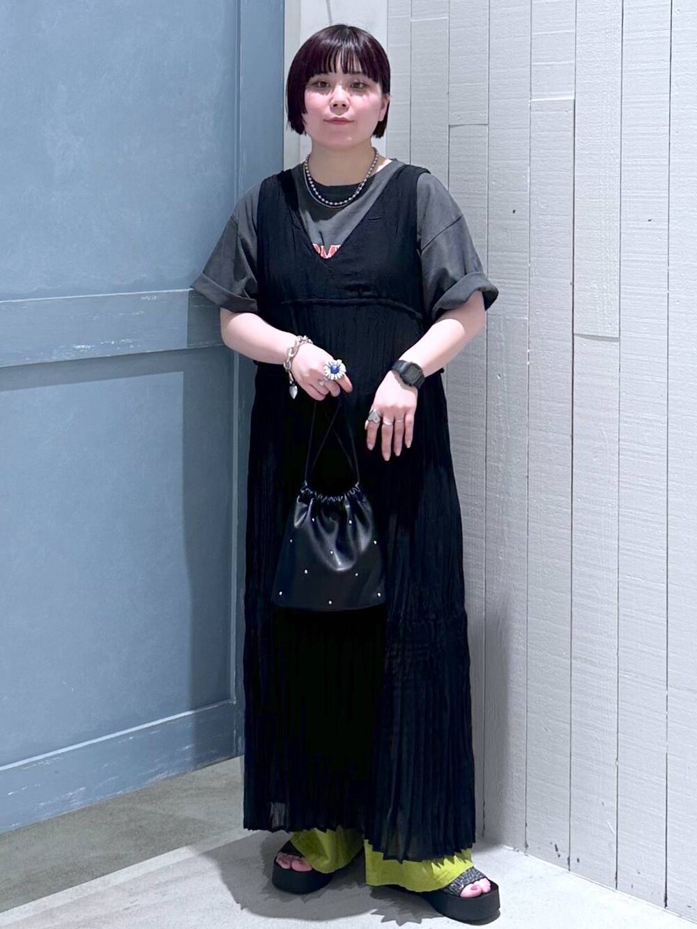 ブラック系のサンダル、ブラック系のショルダーバッグ、グリーン系のスラックスを着用したレディースの夏コーディネートの2枚目の写真