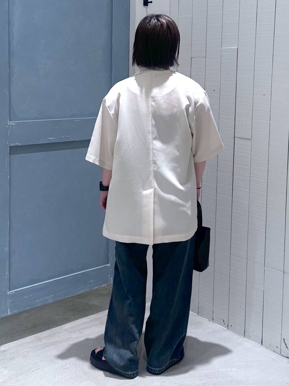 ブルー系のデニムパンツ、ブラック系のショルダーバッグ、ブラック系のサンダルを着用したレディースの夏コーディネートの4枚目の写真