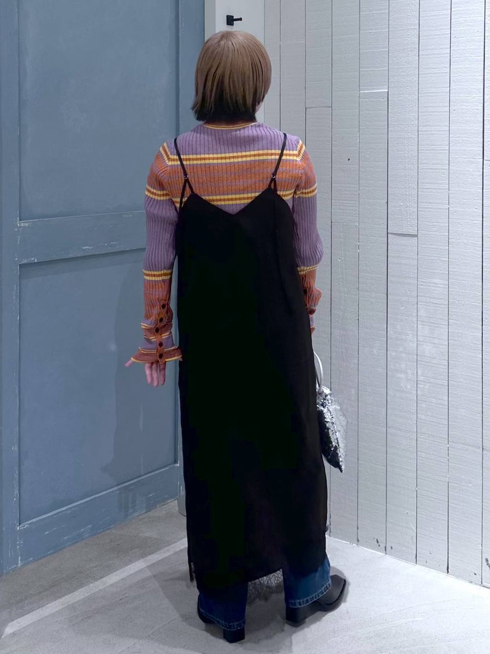 ブルー系のデニムパンツ、ブラック系のパンプス、シルバー系のハンドバッグを着用したレディースの秋コーディネートの5枚目の写真