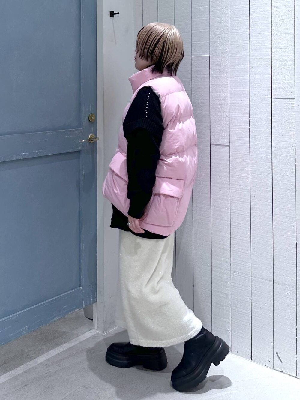 ピンク系のダウンベスト、ブラック系のTシャツ/カットソー、ホワイト系のスカートを着用したレディースの秋コーディネートの5枚目の写真