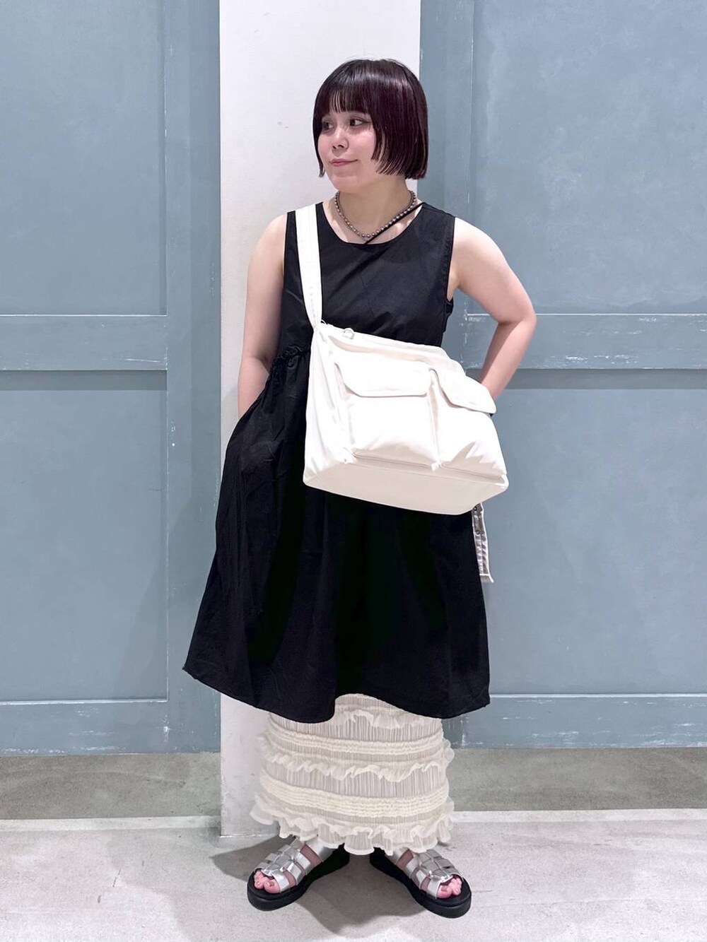 ブラック系のTシャツ/カットソー、ホワイト系のスカート、シルバー系のスニーカーを着用したレディースの夏コーディネートの2枚目の写真