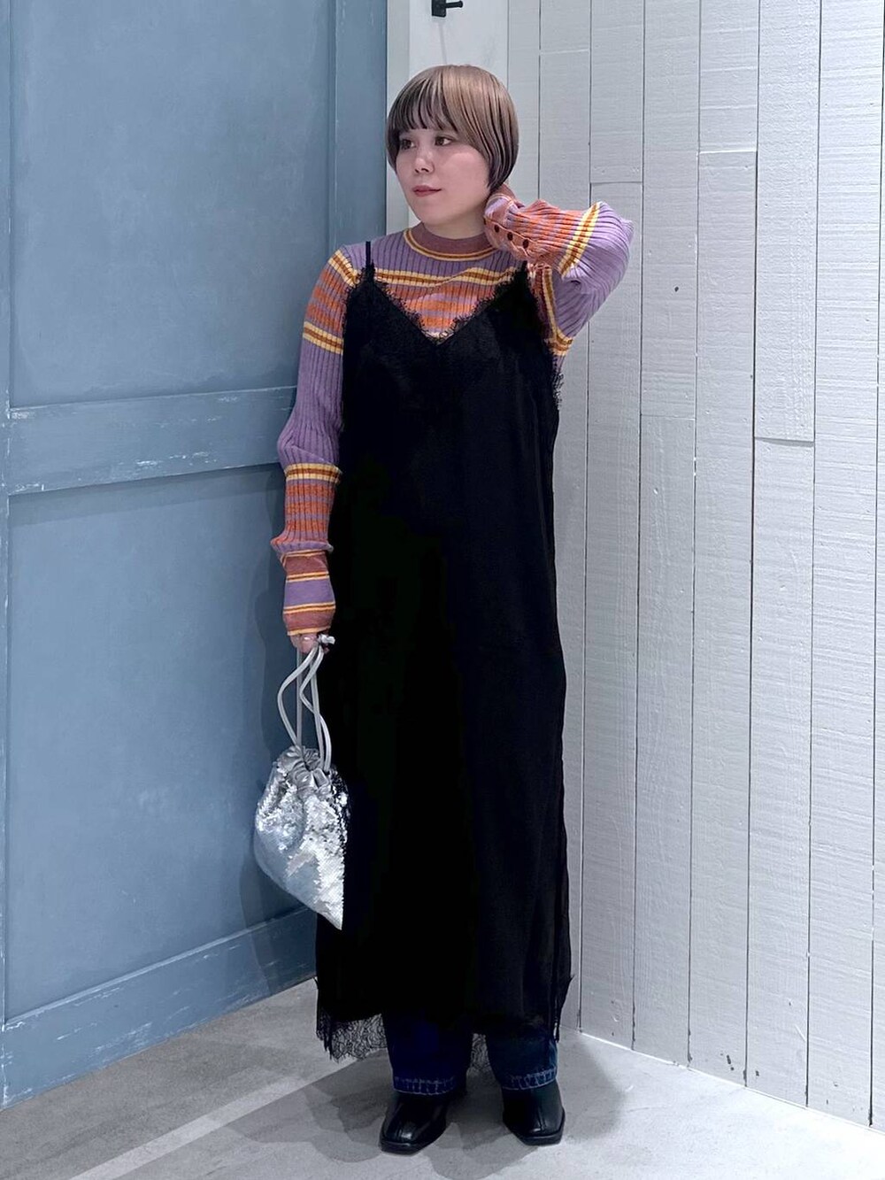 ブルー系のデニムパンツ、ブラック系のパンプス、シルバー系のハンドバッグを着用したレディースの秋コーディネートの3枚目の写真