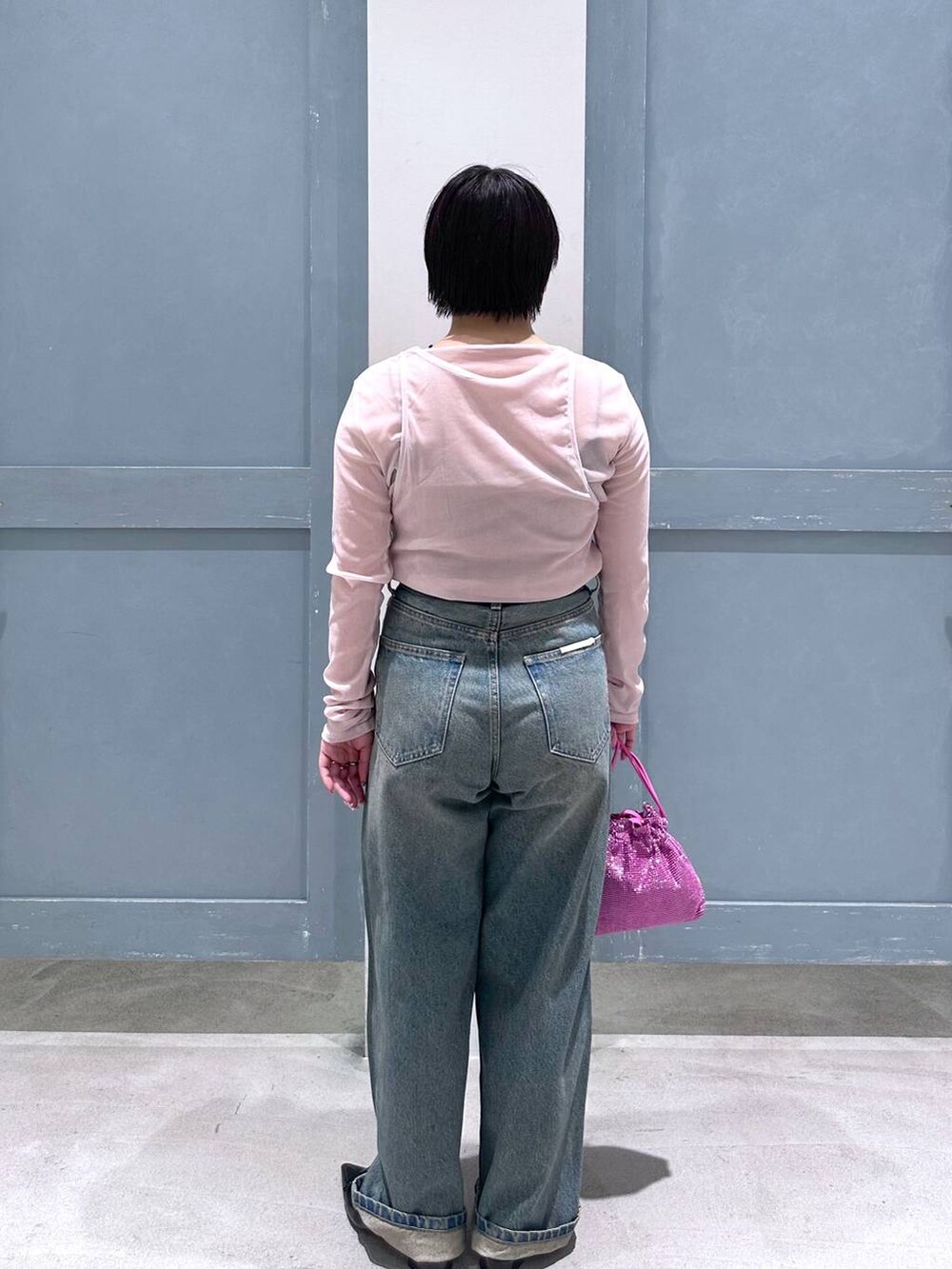 ブルー系のデニムパンツ、ブラック系のパンプス、ピンク系のショルダーバッグを着用したレディースの夏コーディネートの4枚目の写真