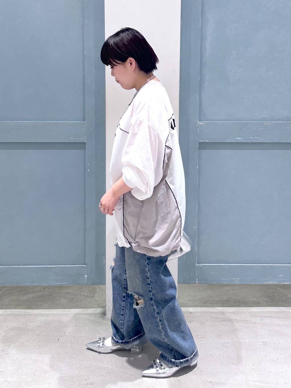 シルバー系のパンプス、シルバー系のショルダーバッグ、ブルー系のデニムパンツを着用したレディースの秋コーディネートの3枚目の写真