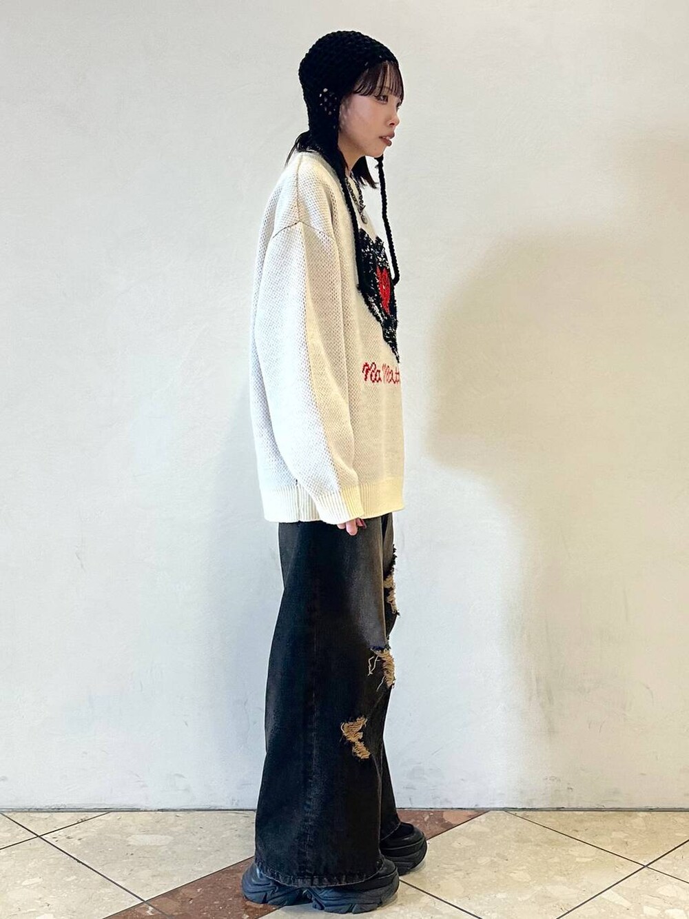 ブラック系のスニーカー、ブラック系のデニムパンツ、ホワイト系のニット/セーターを着用したレディースの冬コーディネートの3枚目の写真