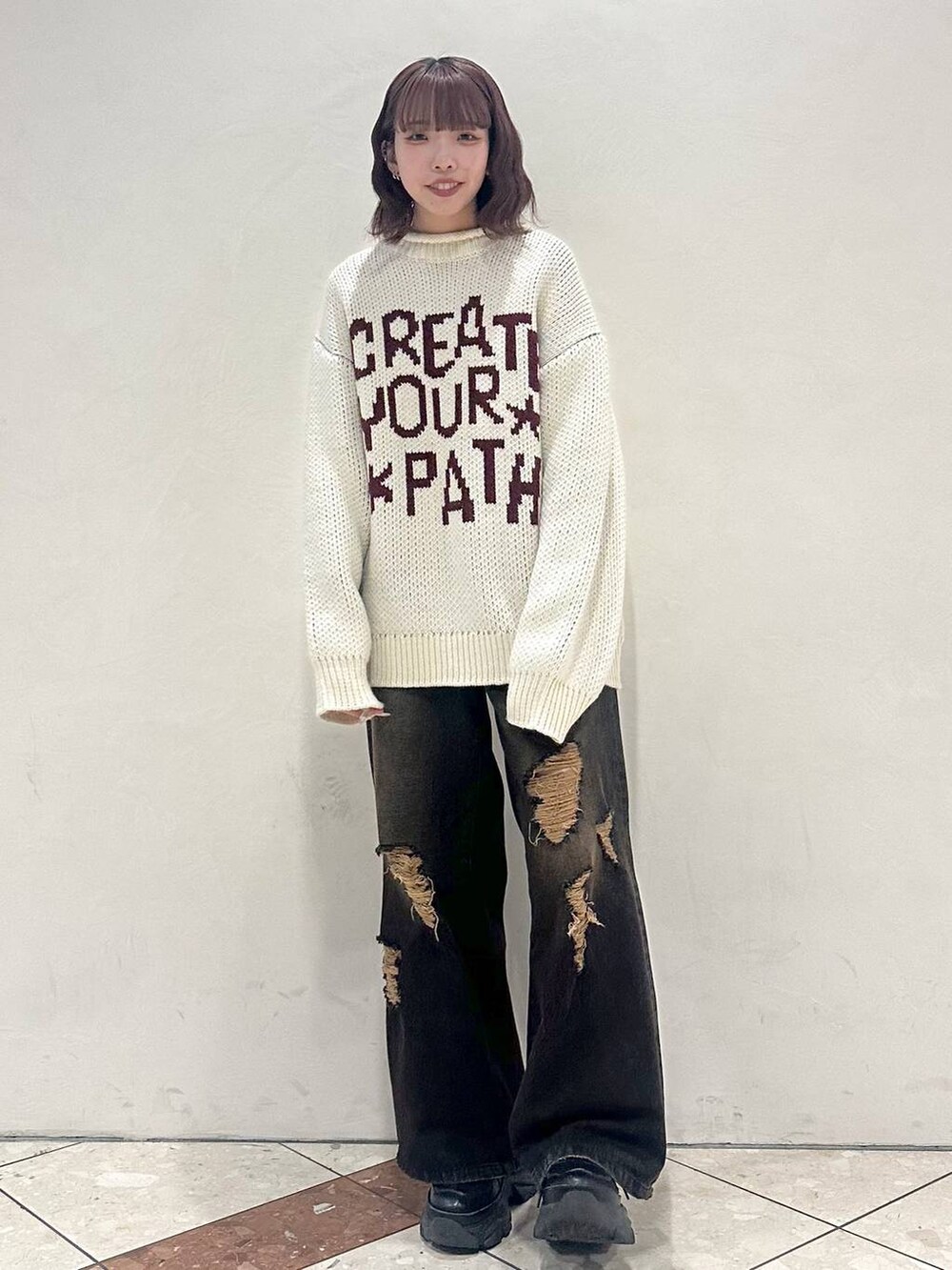 ブラック系のスニーカー、ホワイト系のニット/セーター、ブラック系のデニムパンツを着用したレディースの冬コーディネートの2枚目の写真