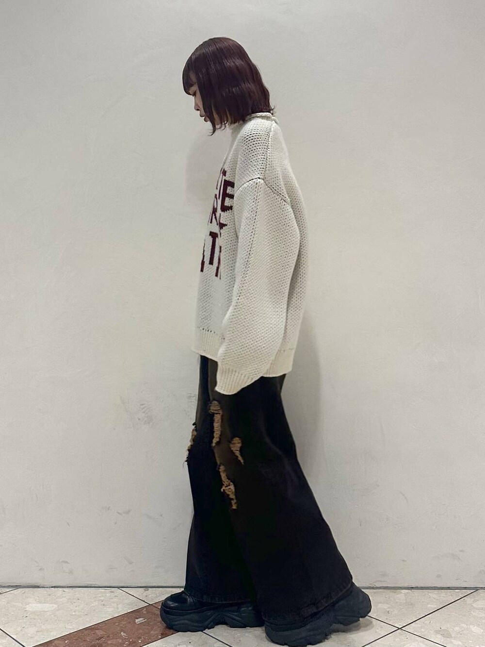 ブラック系のスニーカー、ホワイト系のニット/セーター、ブラック系のデニムパンツを着用したレディースの冬コーディネートの3枚目の写真