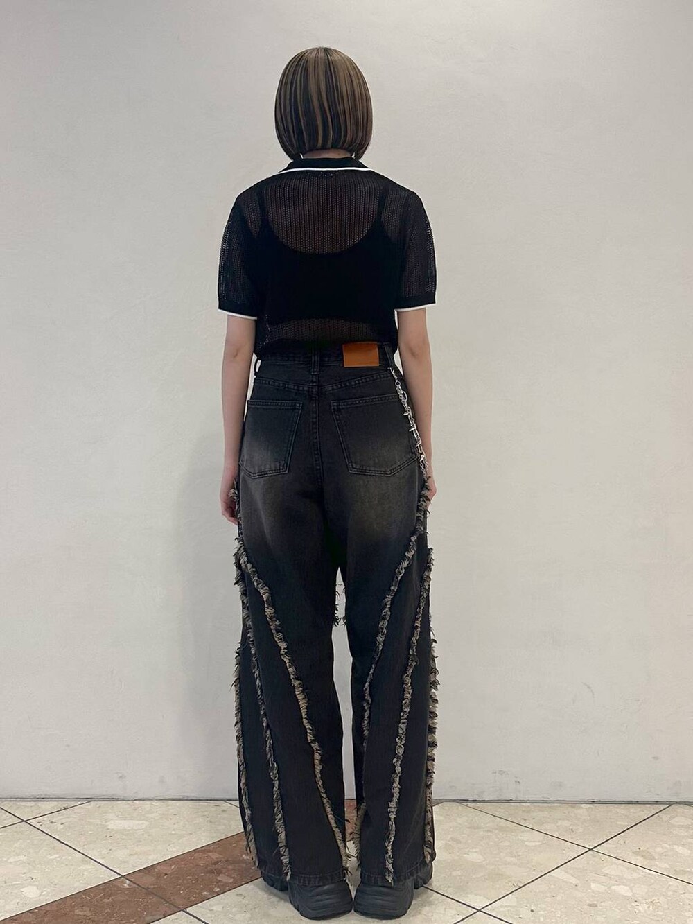 ブラック系のスニーカー、ブラック系のニット/セーター、ブラック系のデニムパンツを着用したレディースの夏コーディネートの4枚目の写真