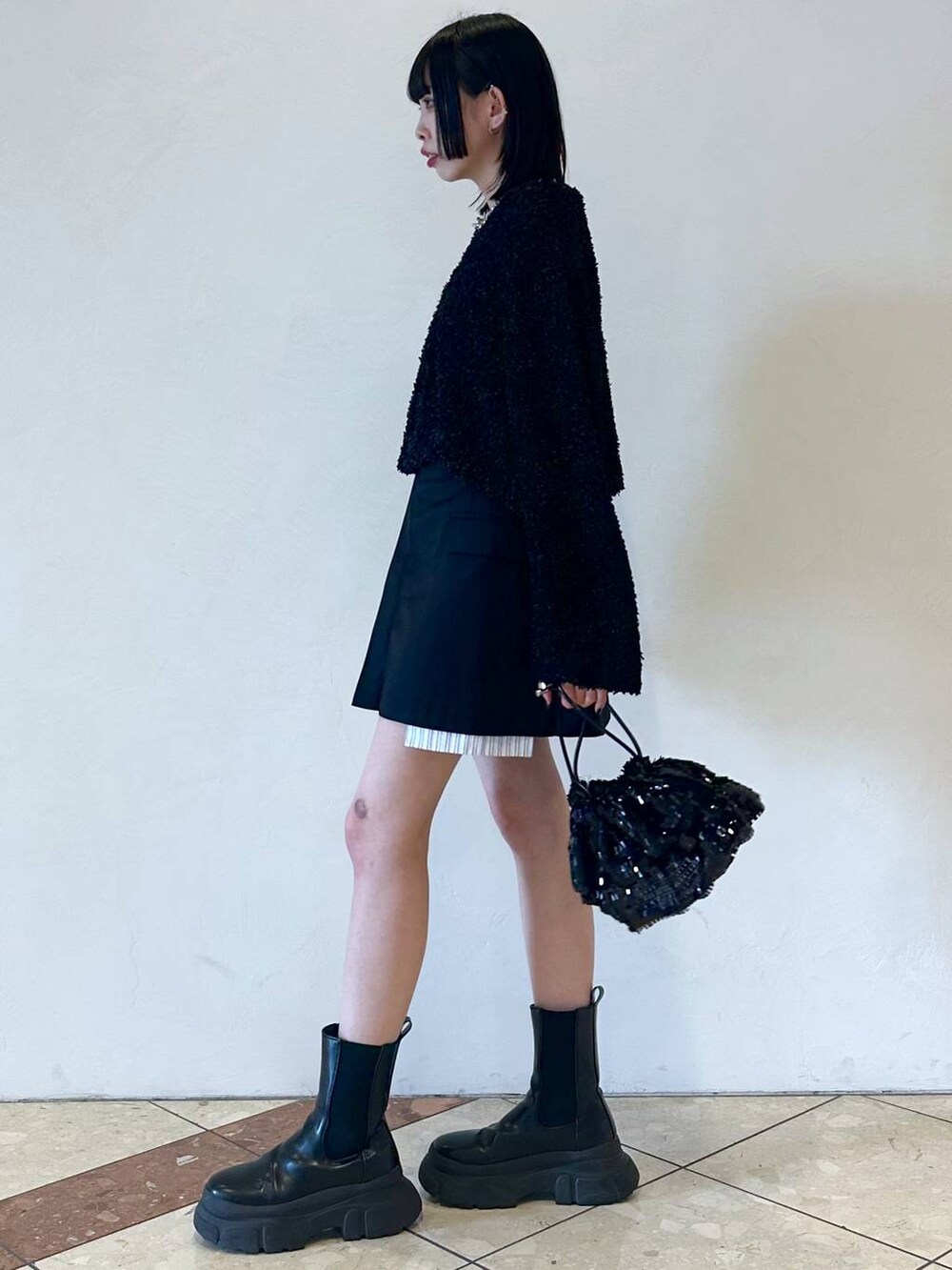 グレー系のタンクトップ、ブラック系のカーディガン/ボレロ、ブラック系のブーツを着用したレディースの春コーディネートの3枚目の写真