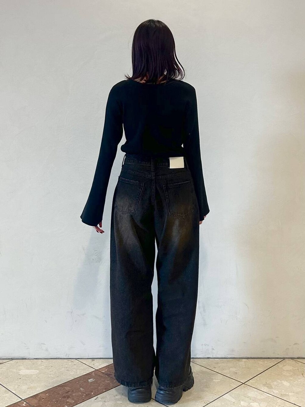 ブラック系のスニーカー、ブラック系のデニムパンツ、ブラック系のニット/セーターを着用したレディースの冬コーディネートの3枚目の写真