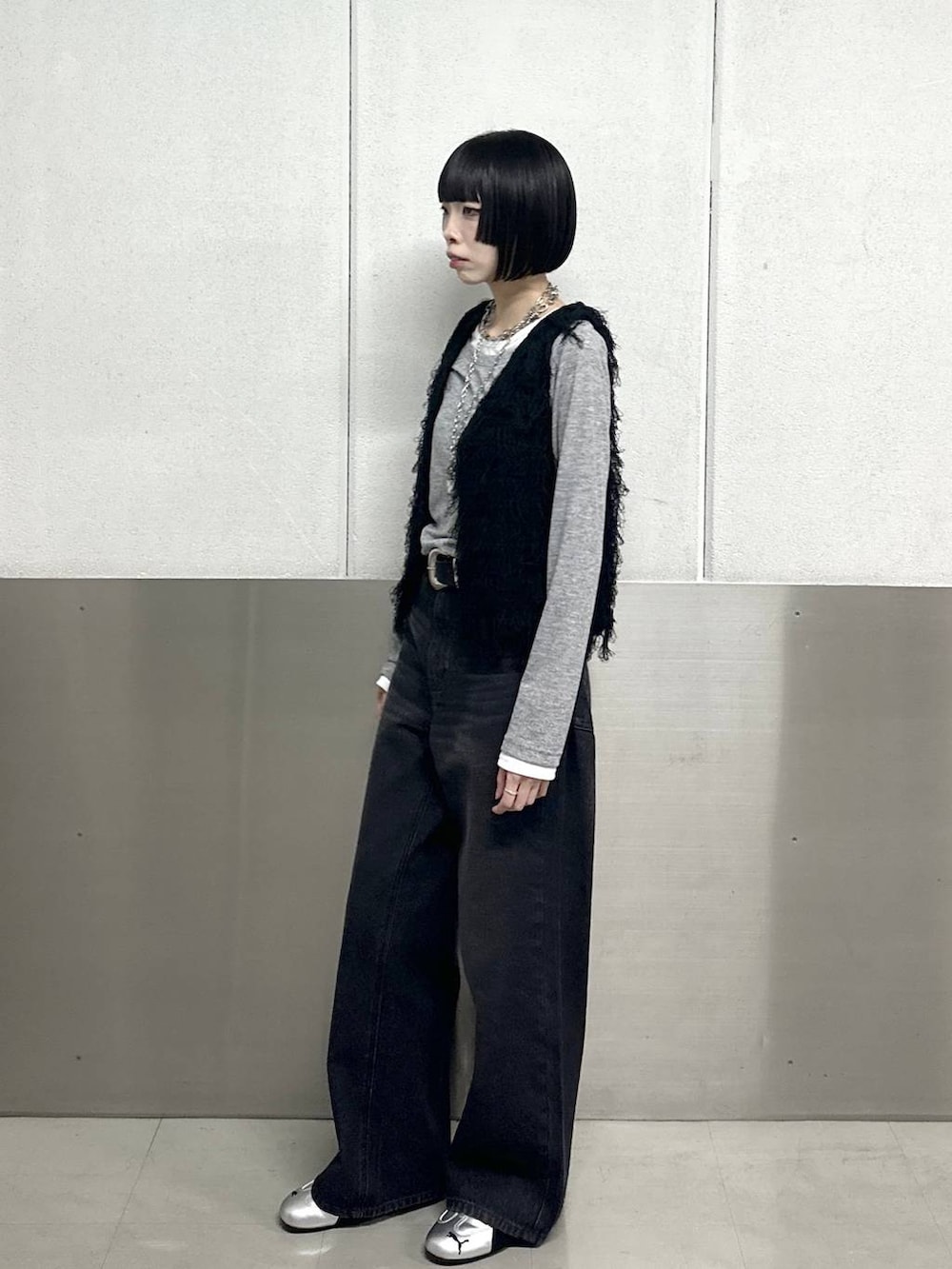 ブラック系のスラックス、ブラック系のベスト、グレー系のTシャツ/カットソーを着用したレディースの春コーディネートの3枚目の写真