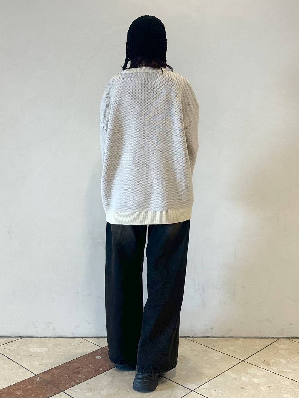 ブラック系のスニーカー、ブラック系のデニムパンツ、ホワイト系のニット/セーターを着用したレディースの冬コーディネートの4枚目の写真