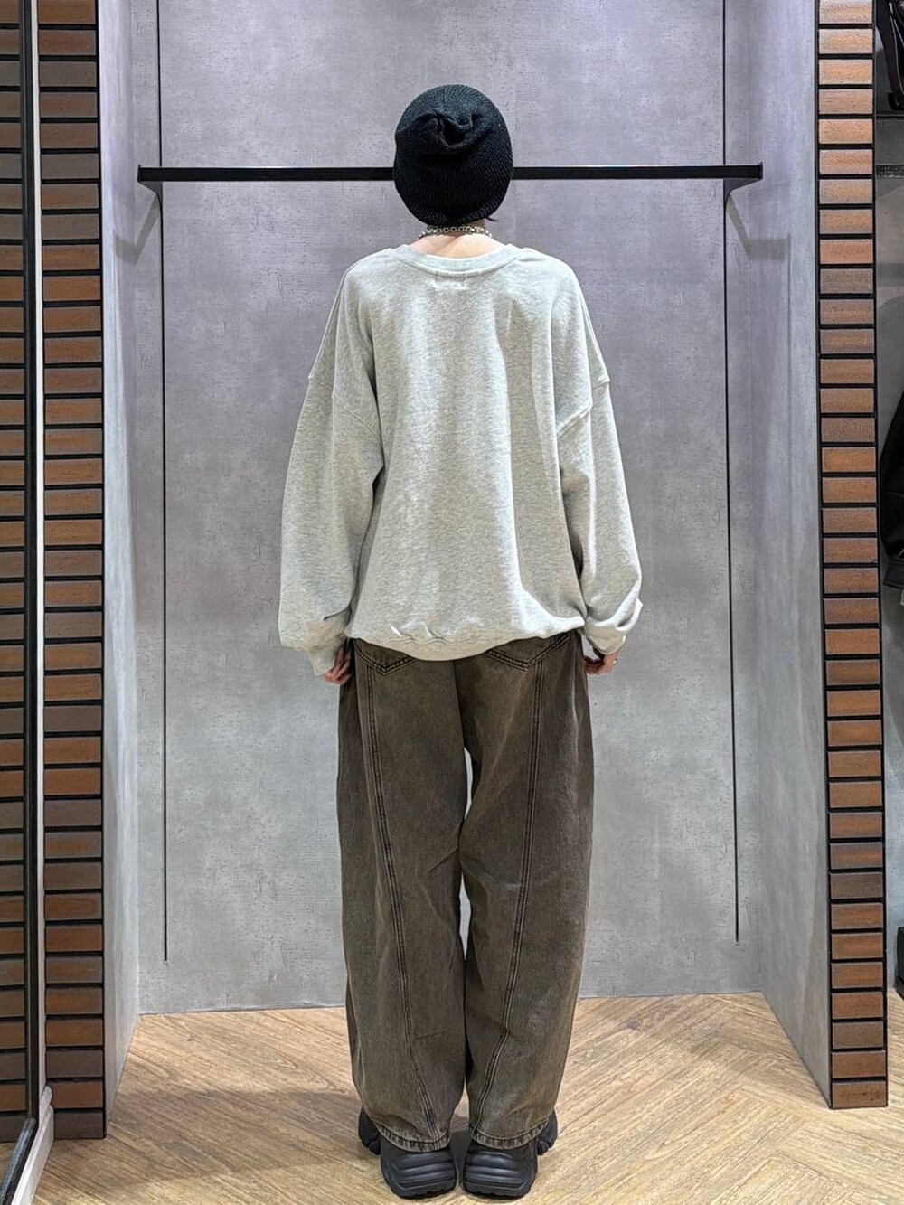 ブラウン系のデニムパンツ、ブラック系のスニーカー、グレー系のスウェットを着用したレディースの秋コーディネートの4枚目の写真