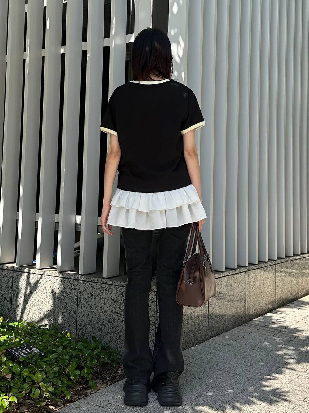 ブラック系のスニーカー、ブラック系のデニムパンツ、ブラウン系のショルダーバッグを着用したレディースの夏コーディネートの4枚目の写真