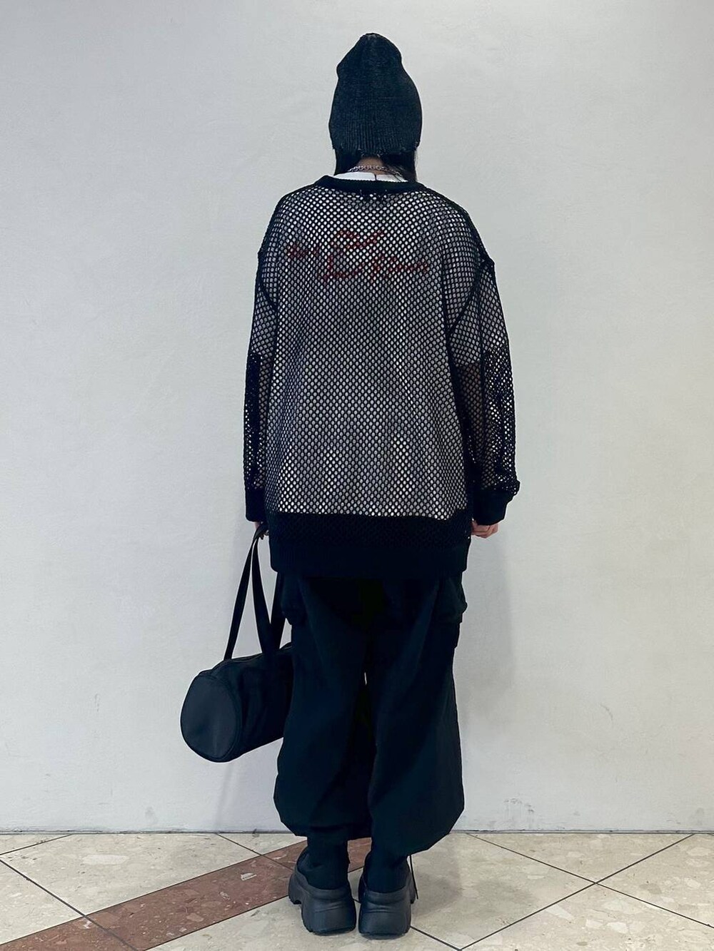 ブラック系のドラムバッグ、ホワイト系のTシャツ/カットソー、ブラック系のブーツを着用したレディースの春コーディネートの3枚目の写真