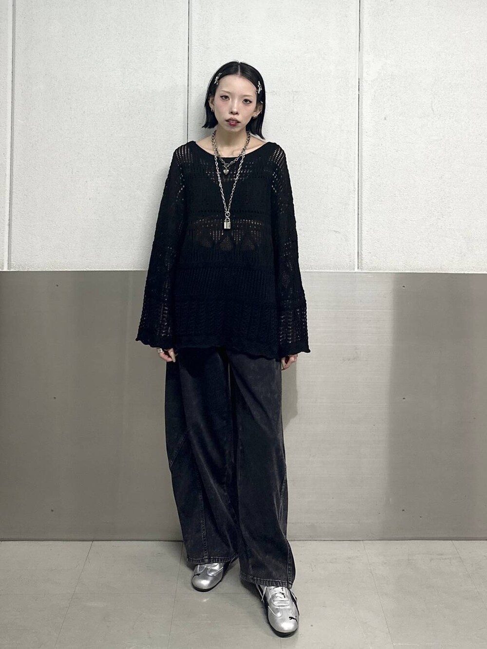 ブラック系のデニムパンツ、ブラック系のニット/セーター、ブラック系のネックレスを着用したレディースの春コーディネートの2枚目の写真