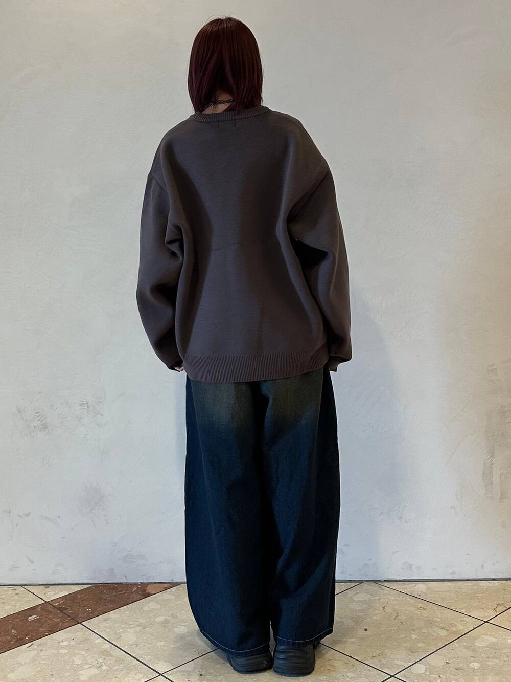 ブラック系のスニーカー、ブルー系のデニムパンツ、グレー系のニット/セーターを着用したレディースの冬コーディネートの4枚目の写真