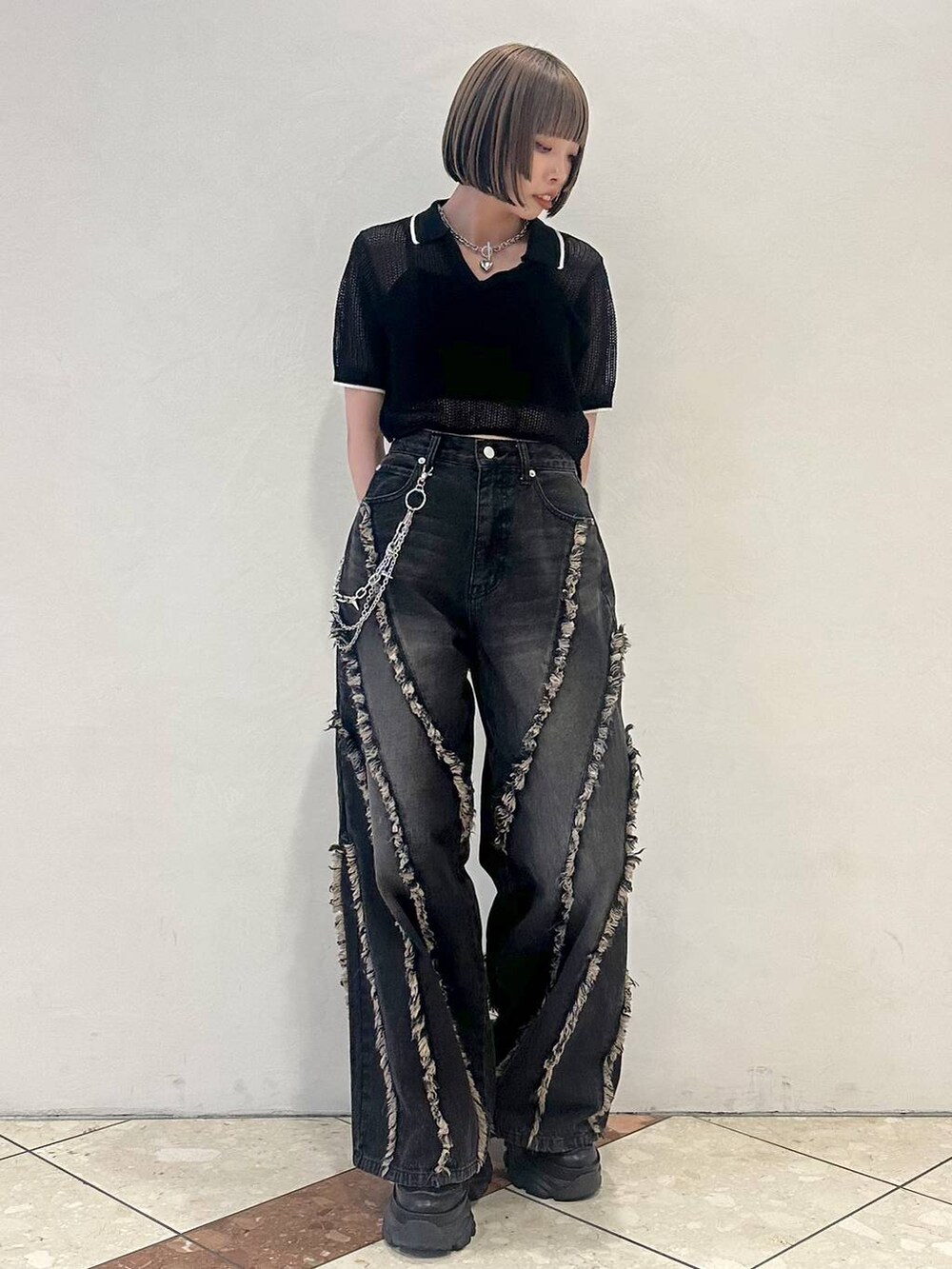 ブラック系のスニーカー、ブラック系のニット/セーター、ブラック系のデニムパンツを着用したレディースの夏コーディネートの2枚目の写真