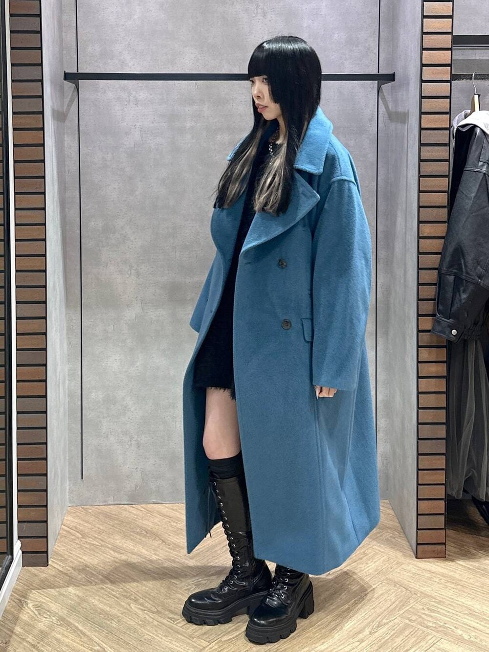 グリーン系のチェスターコート、ブラウン系のその他パンツ、ブラック系のワンピースを着用したレディースの冬コーディネートの3枚目の写真